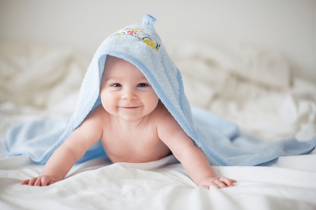 Bebê fofo deitado sorrindo com toalha azul na cabeça