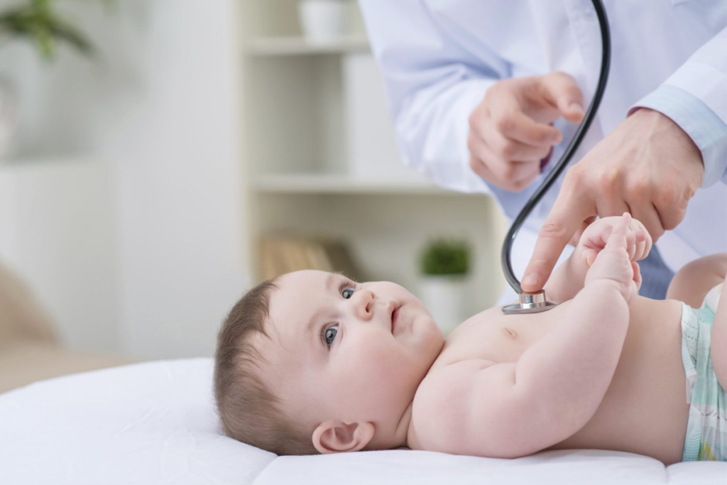 Médica checando os batimentos cardíacos de um bebê deitado.